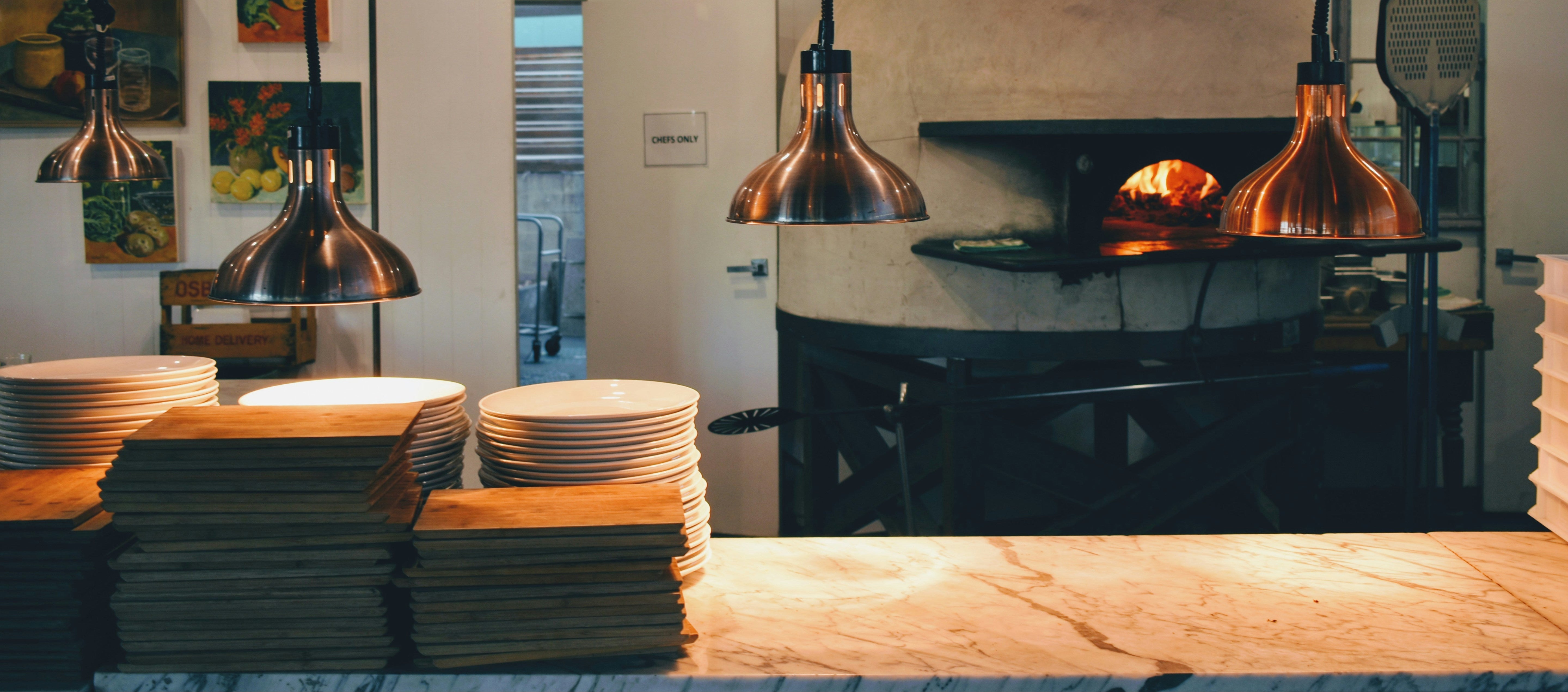 Pizzeria interior with a wood-fired oven and stacks of pizza trays.